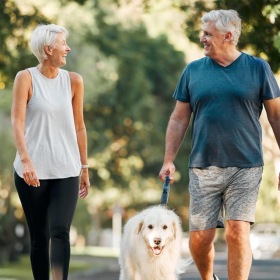 a man and a woman walking a dog on a leash